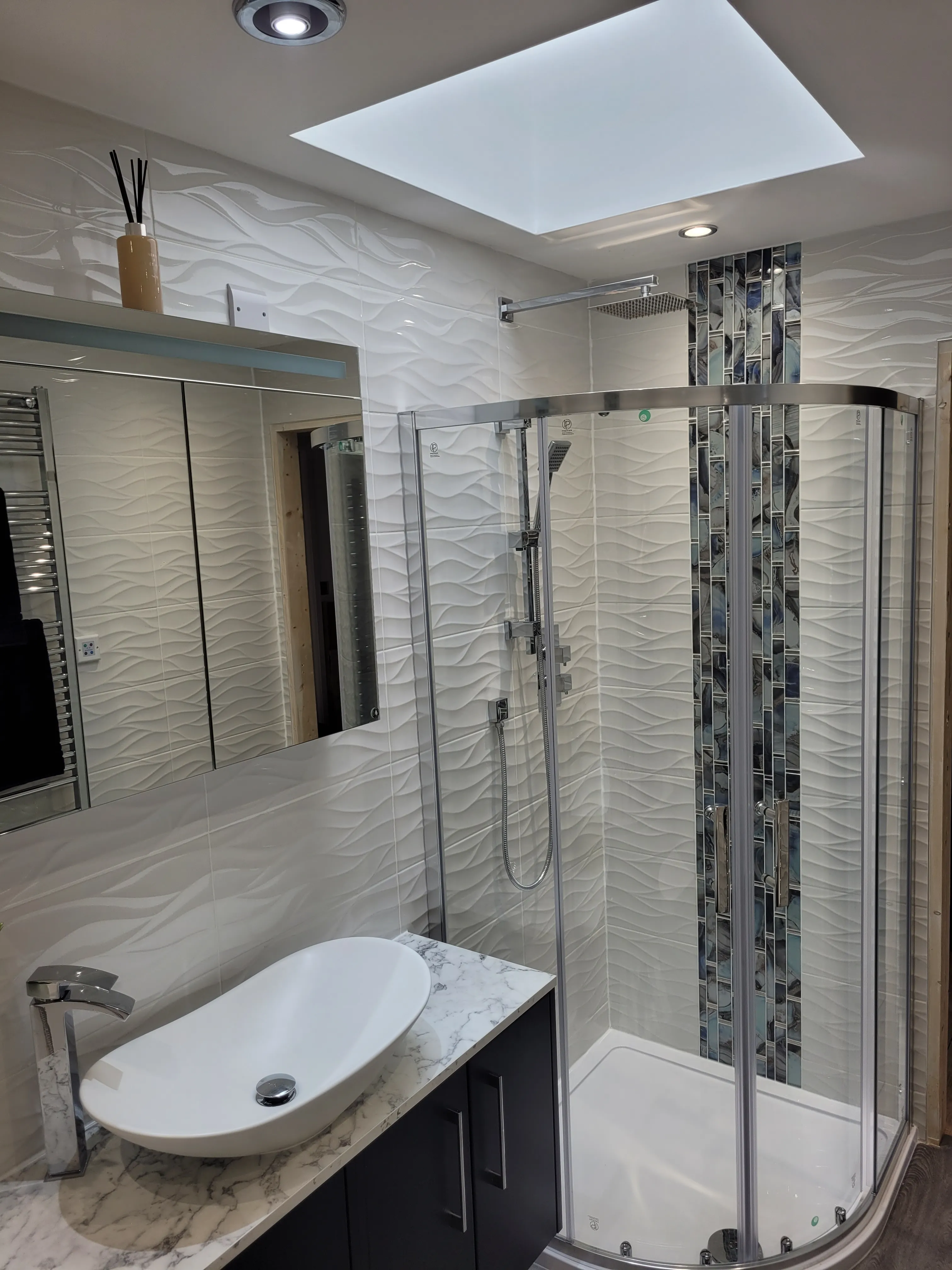 A bathroom with a stand up shower next to a sink.