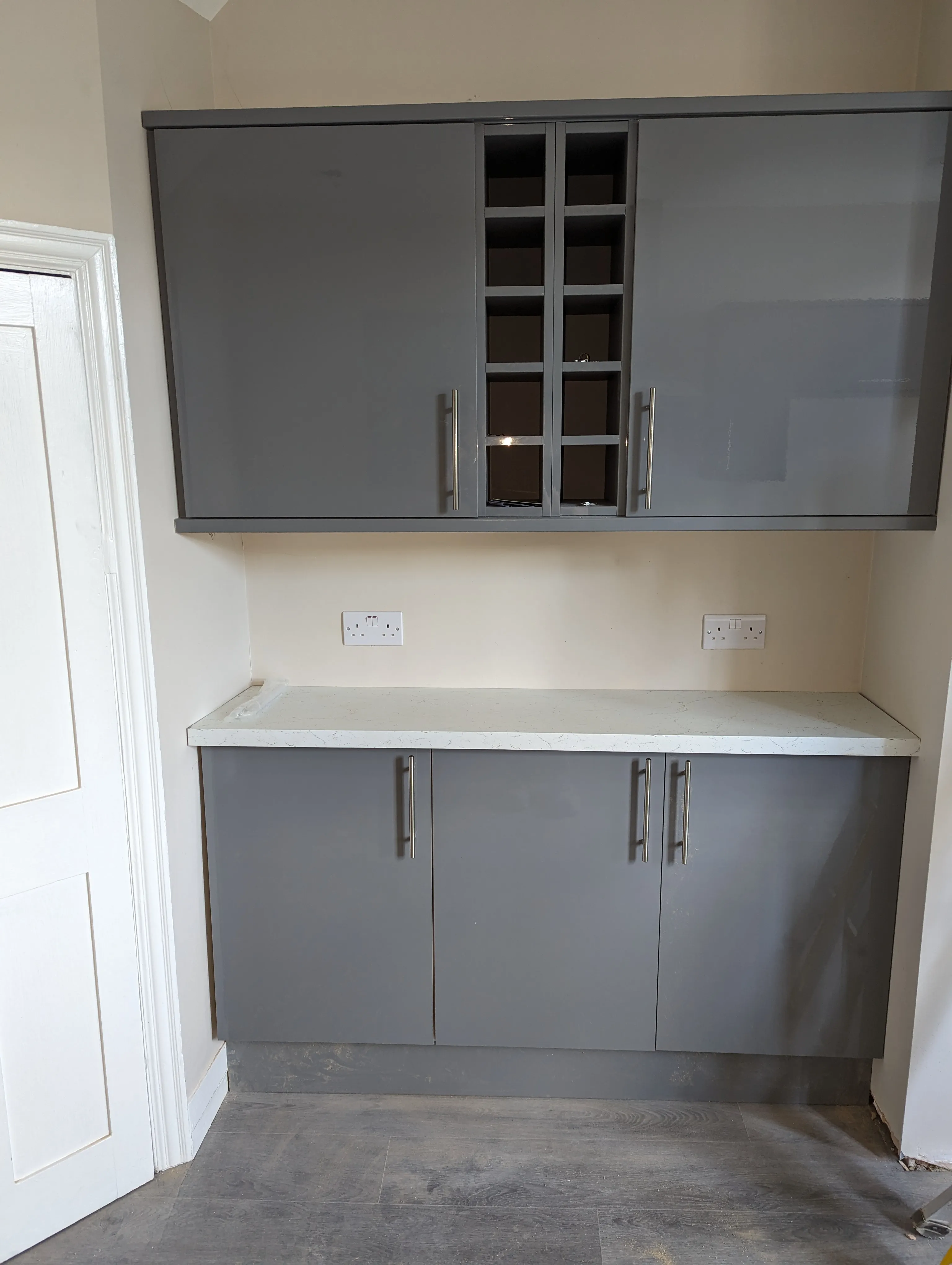 A kitchen with gray cabinets and white counter tops.