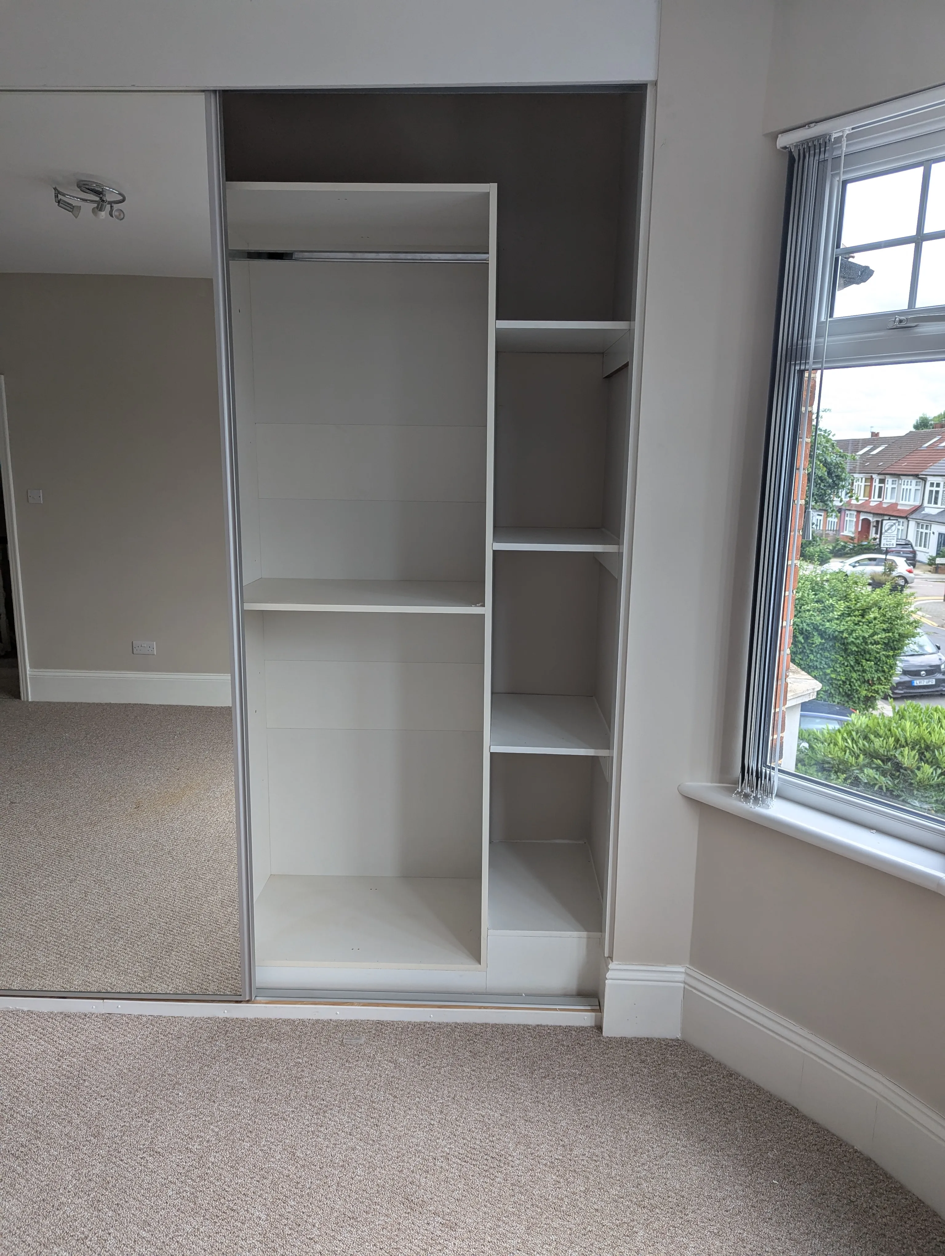 A walk in closet next to a window.
