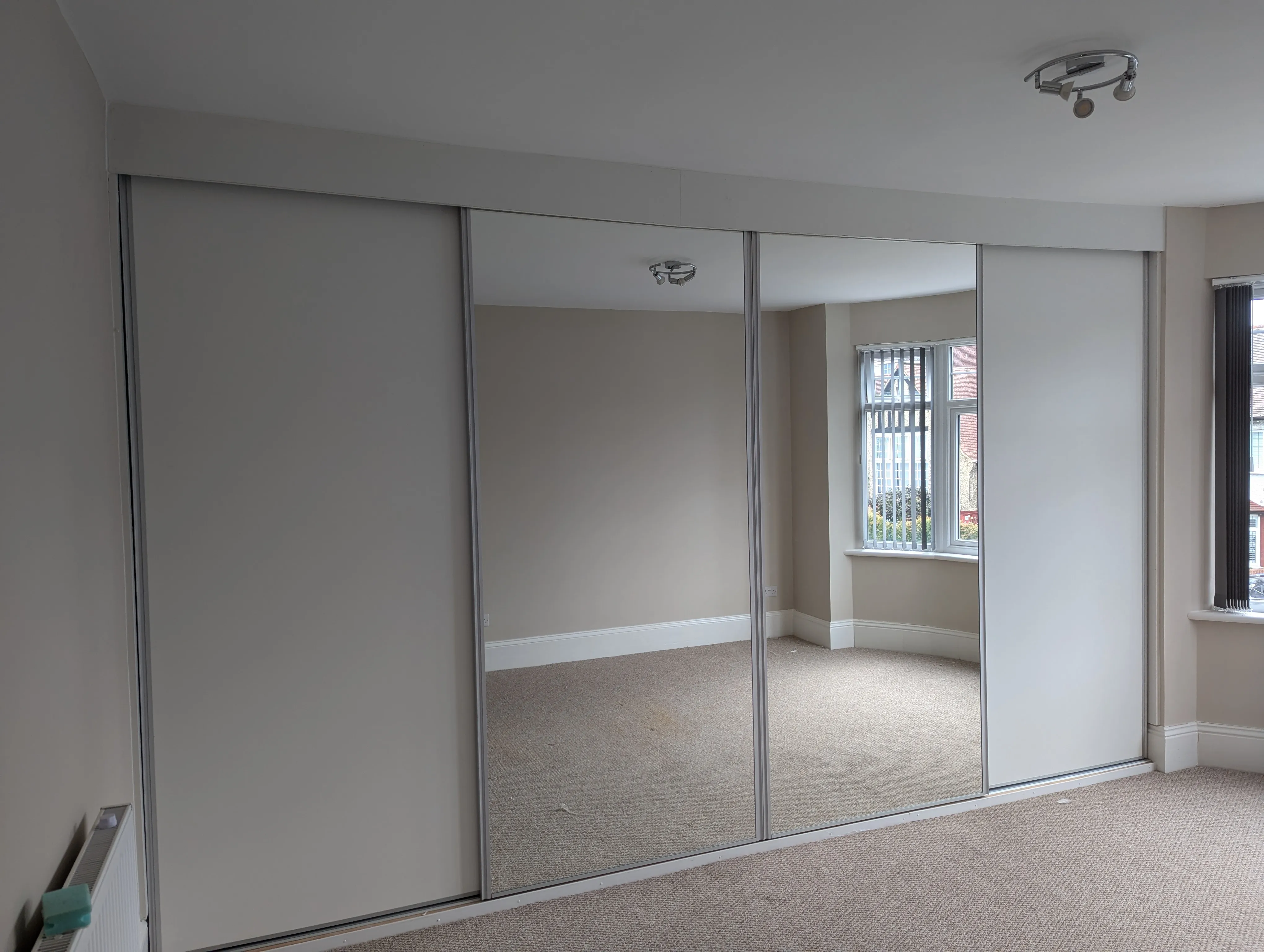 An empty room with a large mirrored closet door.